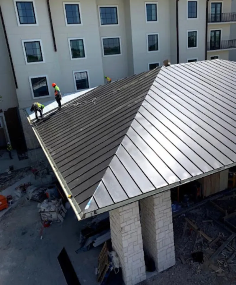 Crew installing standing seam metal roof panels on a commercial project in Manteno